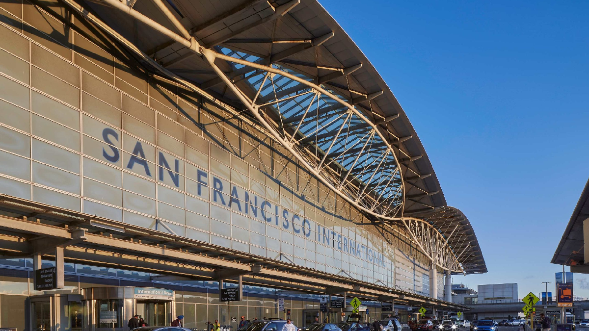 Chauffeur opening door of black luxury sedan for airport pickup at San Francisco International Airport